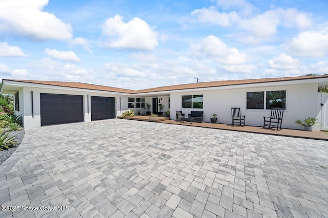 ranch-style home featuring an attached garage, decorative driveway, and stucco siding
