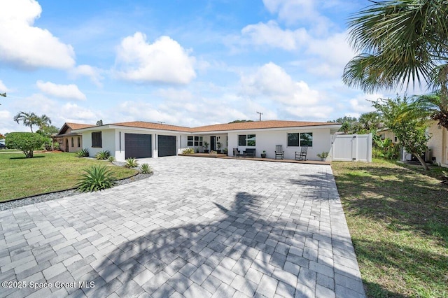 single story home with decorative driveway, a garage, a gate, and stucco siding