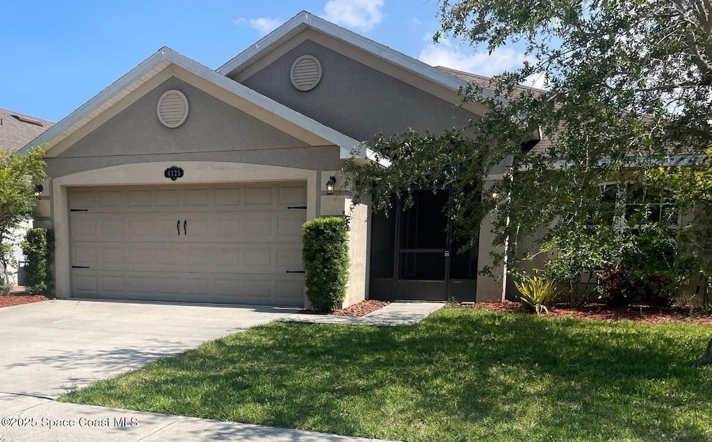 4125 Aria Dr, Melbourne, FL 32904 - view of front of property with an attached garage, driveway, a front lawn, and stucco siding