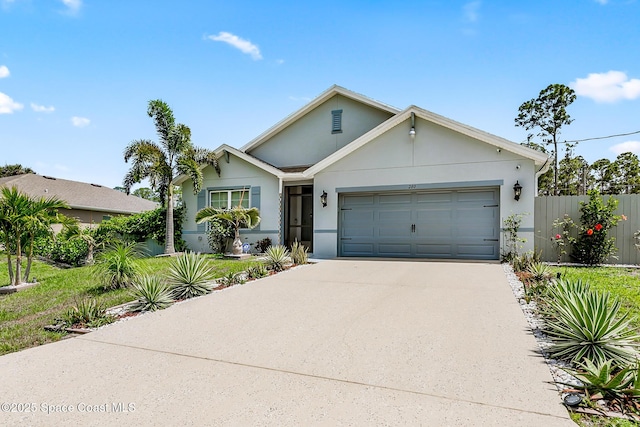 view of front of property with concrete driveway, stucco siding, an attached garage, and fence