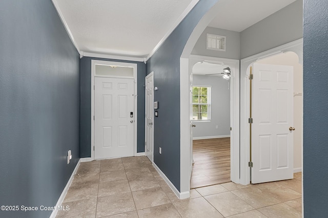 entrance foyer featuring arched walkways, light tile patterned flooring, baseboards, and a ceiling fan