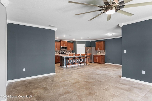 kitchen with appliances with stainless steel finishes, decorative backsplash, baseboards, crown molding, and a ceiling fan