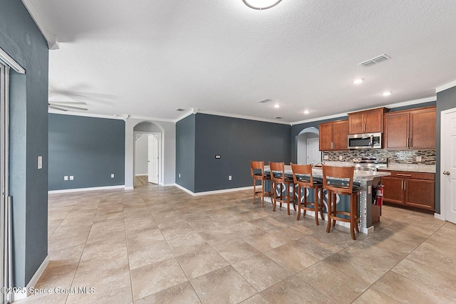 kitchen with stainless steel appliances, arched walkways, baseboards, ornamental molding, and recessed lighting