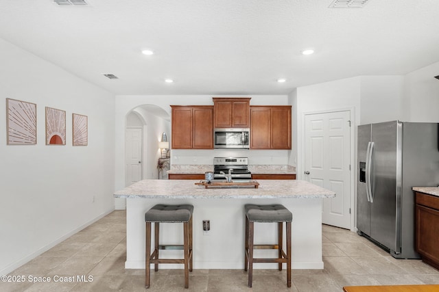 369 Coyote Dr, Cocoa, FL 32927 - kitchen featuring stainless steel appliances, arched walkways, a kitchen island with sink, a breakfast bar area, and recessed lighting