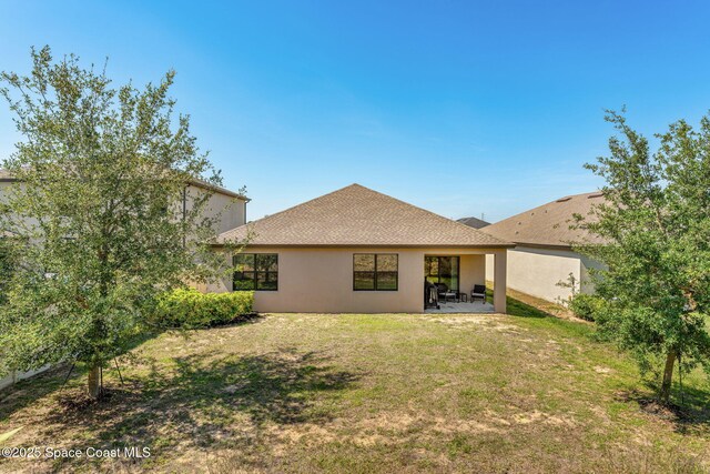 369 Coyote Dr, Cocoa, FL 32927 - rear view of property featuring stucco siding, a patio, a lawn, and roof with shingles