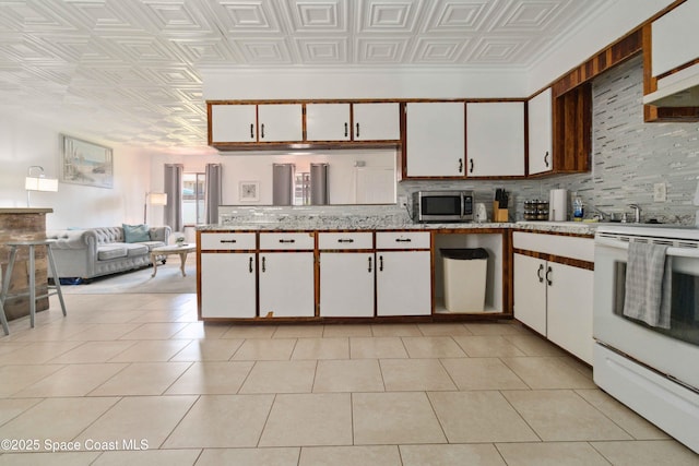 326 Pierce Ave, Cape Canaveral, FL 32920 - kitchen with white electric stove, stainless steel microwave, an ornate ceiling, backsplash, and white cabinets