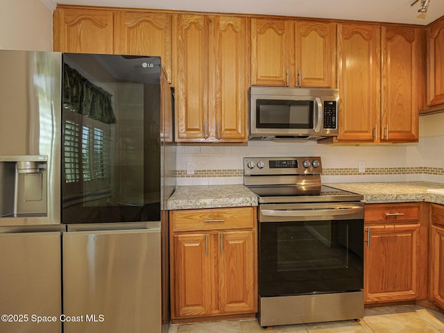 5720 Marina Dr Unit 2, Sebastian, FL 32958 - kitchen featuring appliances with stainless steel finishes, light tile patterned floors, backsplash, light stone counters, and brown cabinetry