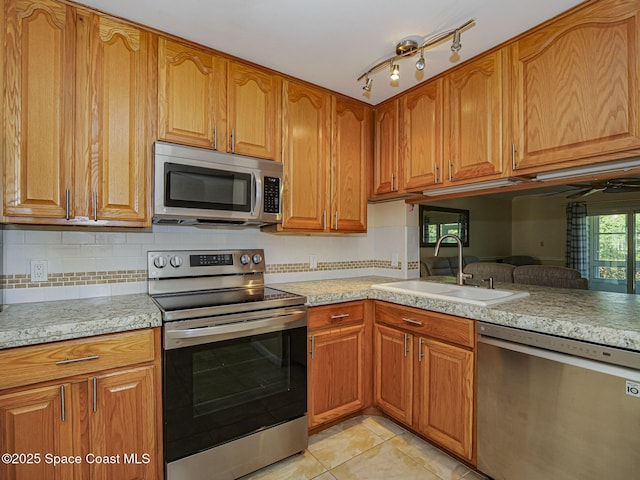 5720 Marina Dr Unit 2, Sebastian, FL 32958 - kitchen featuring appliances with stainless steel finishes, a sink, light tile patterned floors, decorative backsplash, and brown cabinetry