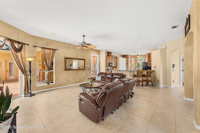living room with a ceiling fan, light tile patterned flooring, arched walkways, baseboards, and recessed lighting