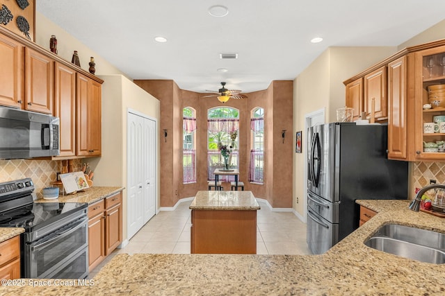 kitchen featuring appliances with stainless steel finishes, a sink, a kitchen island, light tile patterned flooring, and recessed lighting