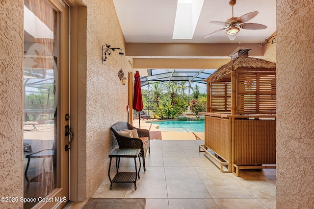 swimming pool featuring a patio area, a ceiling fan, and glass enclosure
