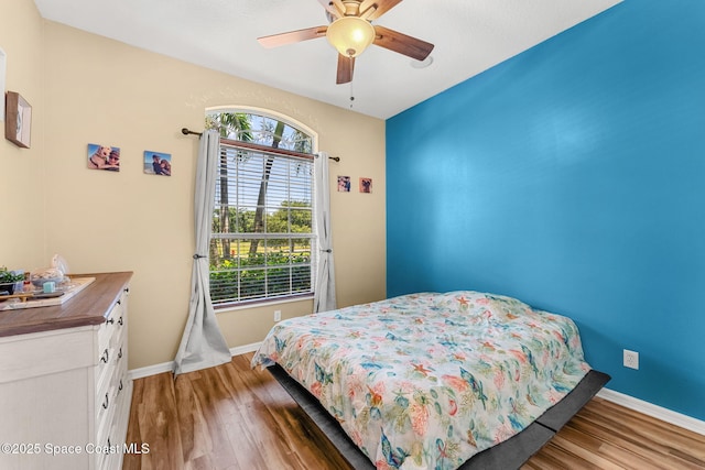 bedroom featuring light wood finished floors, baseboards, and ceiling fan