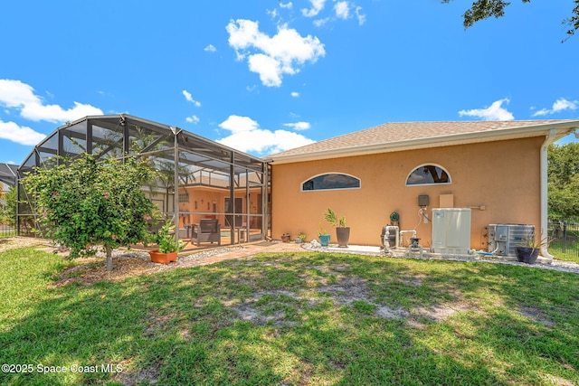 back of property featuring central AC, stucco siding, and a yard