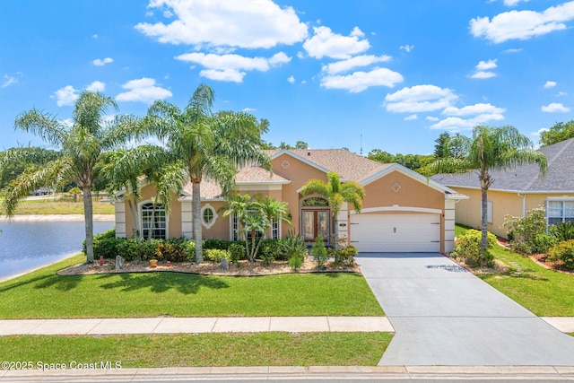 view of front of home with stucco siding, an attached garage, a water view, a front lawn, and driveway