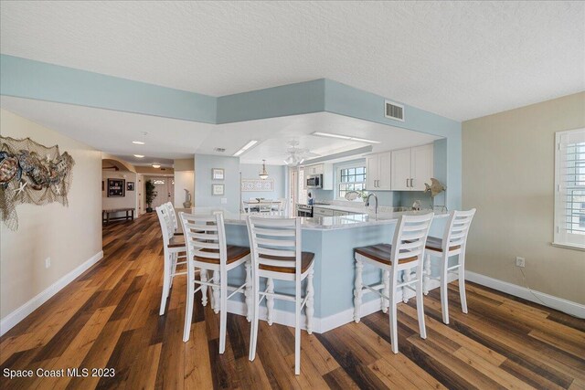3360 S Atlantic Ave Unit 301, Cocoa Beach, FL 32931 - kitchen featuring a peninsula, dark wood-type flooring, stainless steel microwave, light countertops, and baseboards