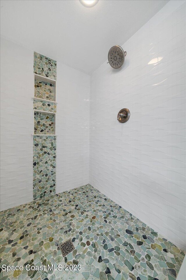 3360 S Atlantic Ave Unit 301, Cocoa Beach, FL 32931 - bathroom with tiled shower, stone finish floors, and tile walls