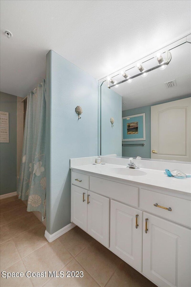 3360 S Atlantic Ave Unit 301, Cocoa Beach, FL 32931 - bathroom with tile patterned floors, vanity, baseboards, and curtained shower
