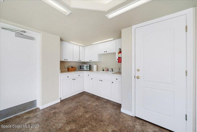 3360 S Atlantic Ave Unit 301, Cocoa Beach, FL 32931 - kitchen with stainless steel microwave, a sink, white cabinetry, baseboards, and light countertops