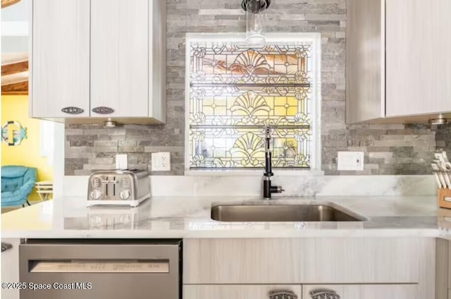 303 Winslow Cir, Cocoa Beach, FL 32931 - kitchen featuring stainless steel dishwasher, light countertops, a sink, and tasteful backsplash