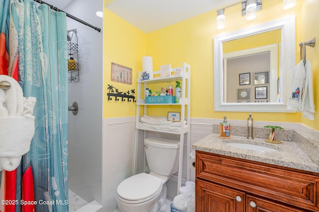 303 Winslow Cir, Cocoa Beach, FL 32931 - bathroom with tile walls, vanity, a wainscoted wall, toilet, and a stall shower