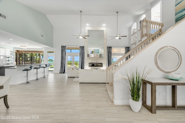 4070 S Tropical Trl, Merritt Island, FL 32952 - living area featuring a towering ceiling, a ceiling fan, stairway, and baseboards
