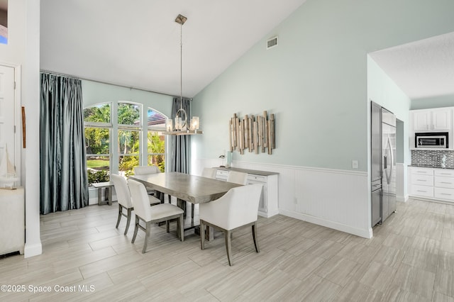 4070 S Tropical Trl, Merritt Island, FL 32952 - dining room featuring high vaulted ceiling, wainscoting, and a chandelier