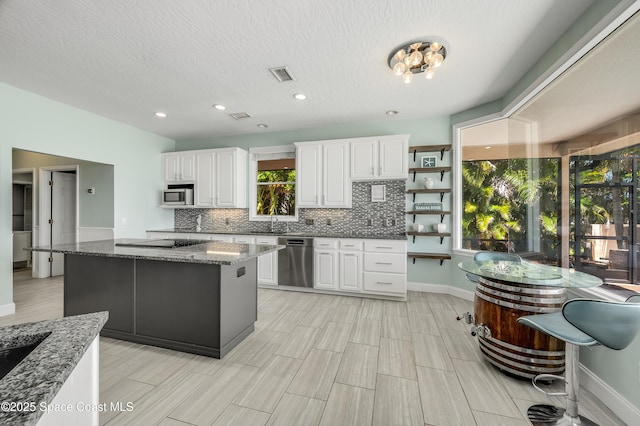 4070 S Tropical Trl, Merritt Island, FL 32952 - kitchen with stainless steel appliances, tasteful backsplash, white cabinetry, baseboards, and dark stone countertops
