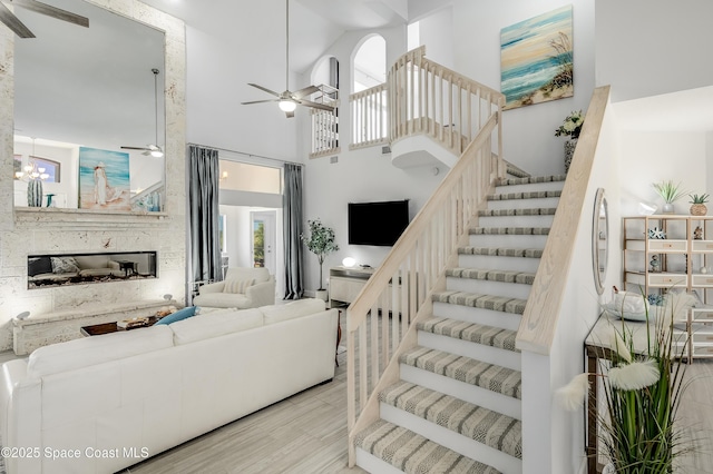 4070 S Tropical Trl, Merritt Island, FL 32952 - living area featuring a ceiling fan, stairs, a towering ceiling, a glass covered fireplace, and wood finished floors