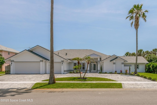 100 Martesia Way, Indian Harbour Beach, FL 32937 - view of front of home with decorative driveway, a garage, stucco siding, and a front lawn