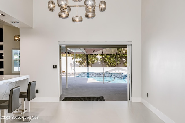 100 Martesia Way, Indian Harbour Beach, FL 32937 - doorway to outside featuring healthy amount of natural light, a sunroom, a chandelier, a high ceiling, and baseboards