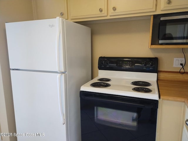 kitchen featuring freestanding refrigerator, range with electric stovetop, stainless steel microwave, and light countertops