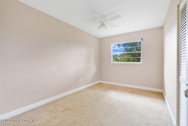 carpeted spare room featuring baseboards and ceiling fan