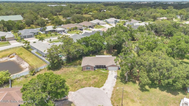 aerial view of property and surrounding area with nearby suburban area and a heavily wooded area