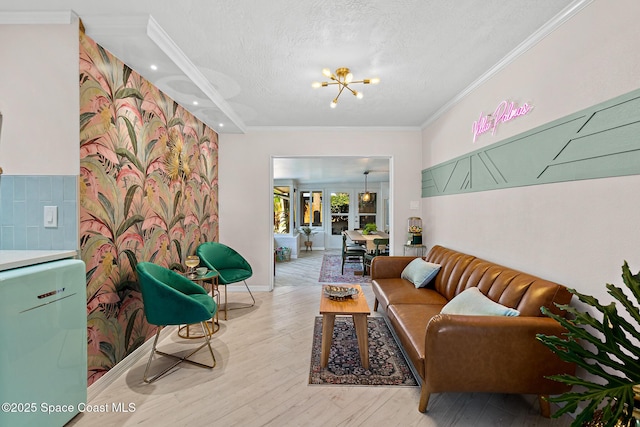 living room featuring crown molding, a chandelier, a textured ceiling, light wood finished floors, and baseboards