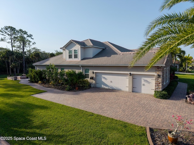 4407 Preservation Cir, Melbourne, FL 32934 - view of home's exterior with a garage, decorative driveway, a yard, a tile roof, and stucco siding