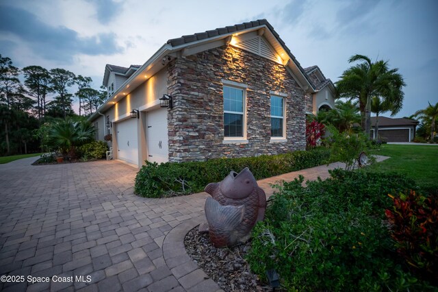 4407 Preservation Cir, Melbourne, FL 32934 - view of side of property featuring stone siding, a garage, and decorative driveway