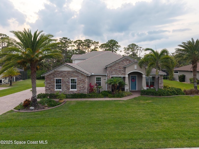 4407 Preservation Cir, Melbourne, FL 32934 - view of front of home featuring stone siding, stucco siding, a tiled roof, and a front yard
