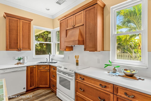 430 Monaco Dr, Indialantic, FL 32903 - kitchen featuring white appliances, a sink, premium range hood, light wood-style flooring, and brown cabinets