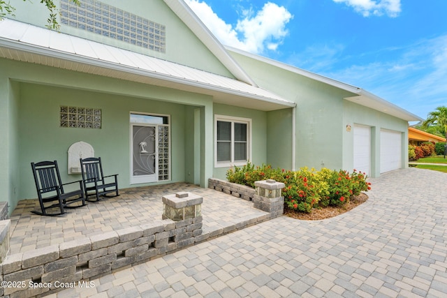 430 Monaco Dr, Indialantic, FL 32903 - entrance to property featuring an attached garage, stucco siding, a standing seam roof, decorative driveway, and metal roof