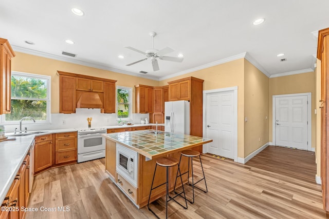 430 Monaco Dr, Indialantic, FL 32903 - kitchen with white appliances, a sink, under cabinet range hood, tile countertops, and light wood finished floors