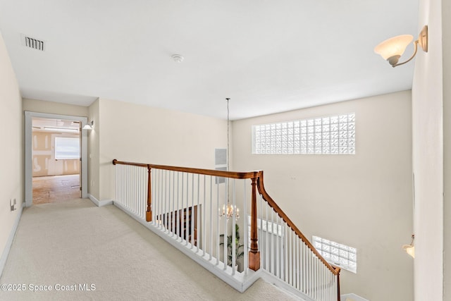 430 Monaco Dr, Indialantic, FL 32903 - hallway featuring healthy amount of natural light, an upstairs landing, carpet, and a chandelier