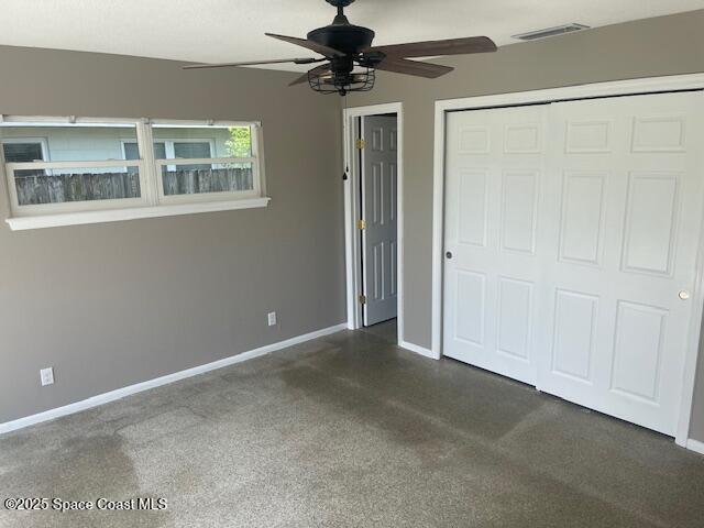 unfurnished bedroom with baseboards, dark colored carpet, and ceiling fan