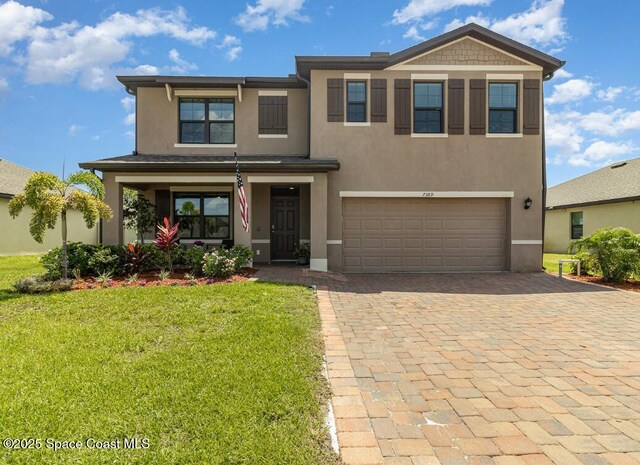7389 Tourmaline Dr, Grant-Valkaria, FL 32949 - view of front facade with decorative driveway, stucco siding, a front lawn, and an attached garage