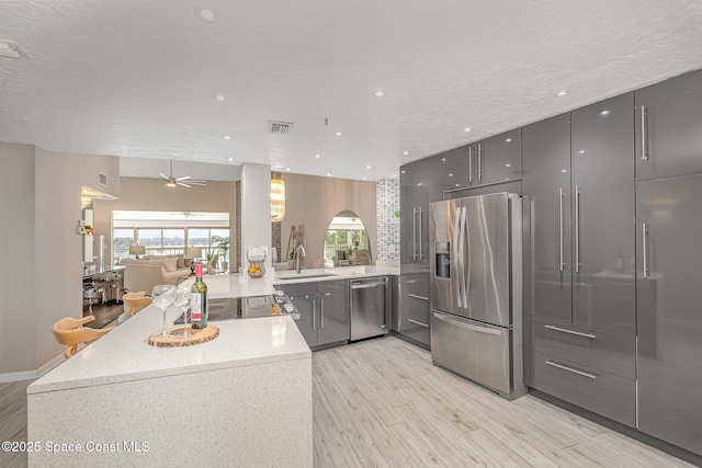 343 N Tropical Trl Unit 404, Merritt Island, FL 32953 - kitchen with stainless steel appliances, a sink, light wood-style floors, open floor plan, and gray cabinets