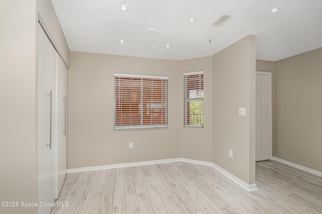 343 N Tropical Trl Unit 404, Merritt Island, FL 32953 - unfurnished bedroom with light wood finished floors, baseboards, recessed lighting, a closet, and a textured ceiling
