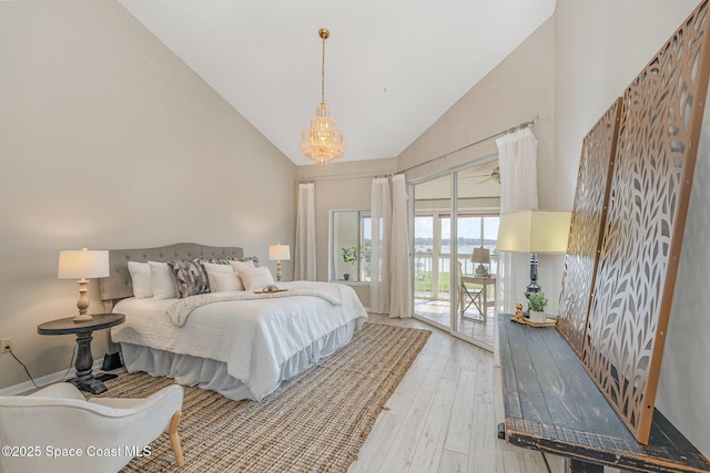 343 N Tropical Trl Unit 404, Merritt Island, FL 32953 - bedroom with access to outside, light wood-style floors, high vaulted ceiling, and a chandelier