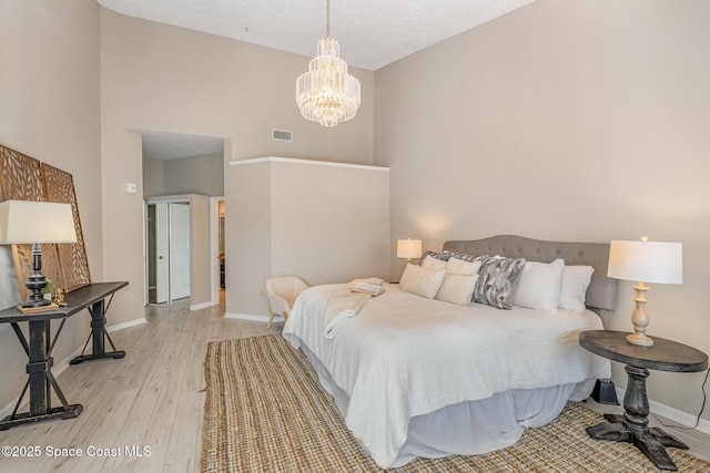 343 N Tropical Trl Unit 404, Merritt Island, FL 32953 - bedroom featuring light wood-style flooring, a towering ceiling, a chandelier, and baseboards
