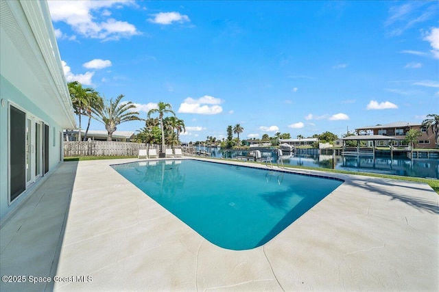 view of swimming pool with a patio area, a water view, and fence
