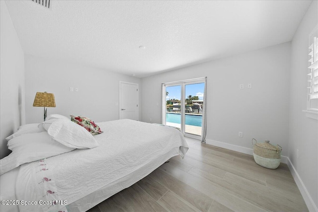 bedroom with access to exterior, light wood-style floors, and baseboards