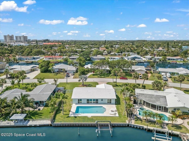 aerial perspective of suburban area featuring a pool and a nearby body of water